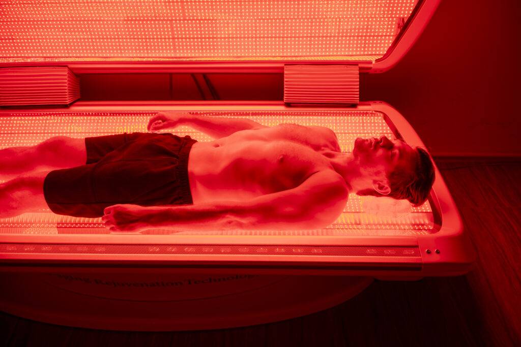 A person reclining on a red-light therapy bed
